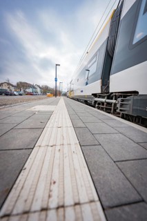 View along an empty sidewalk at a train station under a grey sky, opening of the Hermann Hesse