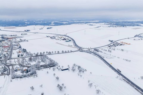Snow-covered intersection in the middle of a vast winter landscape with surrounding villages,