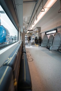 Interior view of a modern train with windows and folding seats, Siemens Micro Plus B battery