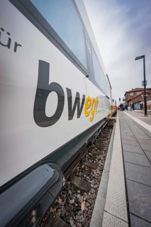 Side close-up of a moving branded train standing on the railway track, with clear sky in the