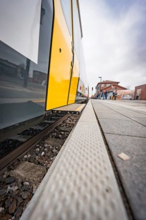 Close-up of a yellow train on a railroad track with focus on the rails, battery electric train