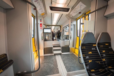 Interior of a modern train with grey and yellow elements and vacant seats, Siemens Micro Plus B