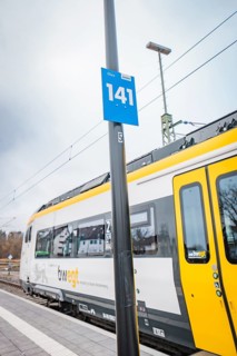 Side view of a yellow train with a track sign on the platform, battery electric train Siemens Micro