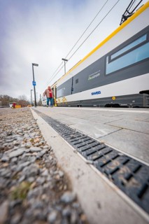 Person walking next to a modern yellow train on the platform, Siemens Micro Plus B battery electric