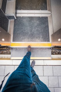 View from above of a passenger crossing the platform. A dynamic perspective with concrete paving,