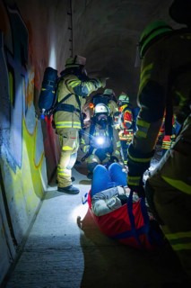 Firefighters provide first aid to an injured person in a dark tunnel, fire drill on the
