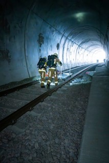 Firefighters in protective suits walk through a dark tunnel on tracks, fire drill on the Hermann