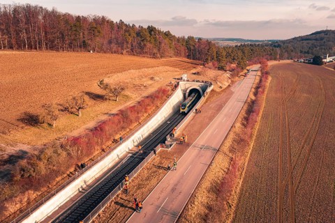 Aerial view of a train near a railway tunnel with emergency services and surrounding landscape,