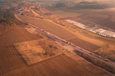 Aerial view of emergency vehicles on country road with visible tunnel and extensive fields at dusk,