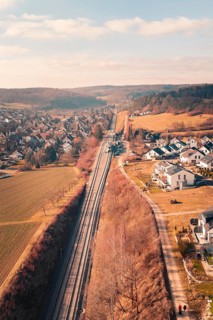 Aerial view of a village with railroad tracks surrounded by fields and hills, fire drill on the