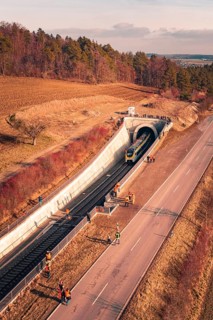 Train leaves a railway tunnel surrounded by emergency services and surrounding countryside, fire