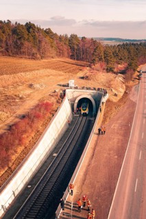 Train is just entering a railway tunnel surrounded by landscape and trees in aerial view, fire
