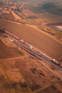 Long row of emergency vehicles on country road with extensive landscape views at dusk, fire drill