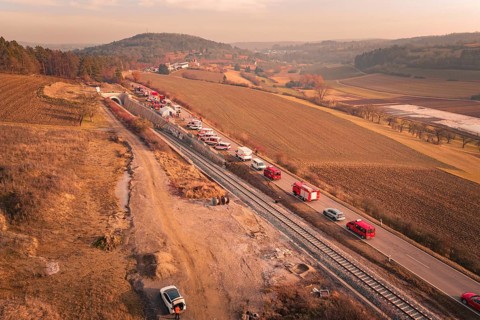 Fire trucks on a country road next to railroad tracks at sunset in a hilly landscape, fire drill on