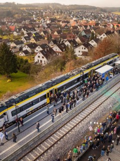 Train in rural areas stops along the platform with numerous observers, opening of the Hermann Hesse