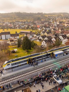 Train stops in a city, people flock onto the platform surrounded by buildings, opening of the