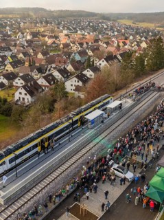 A train stops in a village, many people wait at the platform, opening of the Hermann Hesse Railway,