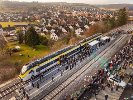 Arrival of the train, greeted by people, in a small village surrounded by nature, opening of the