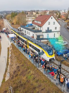 Regional train at a station event with crowds and rain of confetti in a city environment, opening