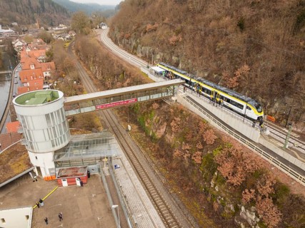 Landscape view of a railway station with bridge, hills and city in the background, opening of the