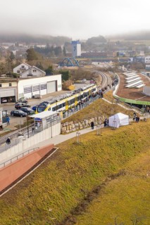 Landscape view with train and people along a railway line in an urban environment, opening of the