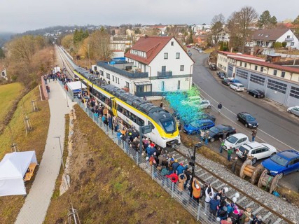 Aerial view of a train on a route with people and rain of confetti next to buildings during an