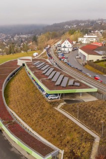 Solar panels on a hill in an urban landscape with cars and houses, opening of the Hermann Hesse