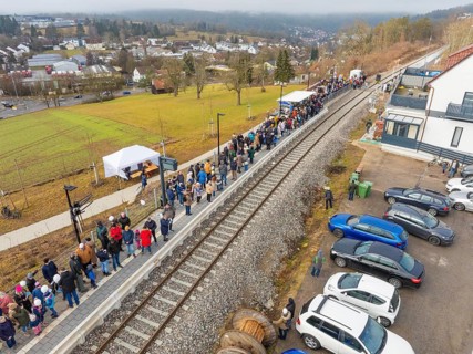 Station with lots of people waiting and parked cars in a rural area, opening of the Hermann Hesse