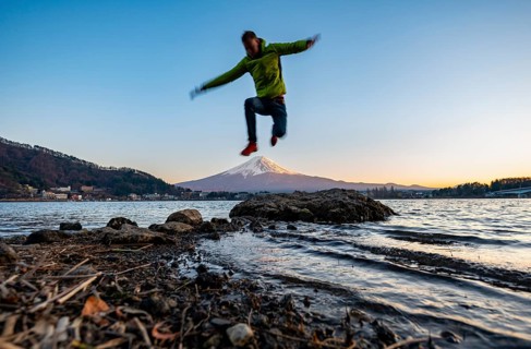 Young man jumping, Lake Kawaguchi, view of Mount Fuji volcano at sunset, Yamanashi Prefecture,