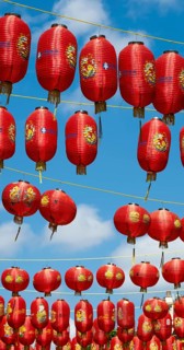 Red Chinese lanterns hanging on yellow lines against a blue sky, London, England, Great Britain