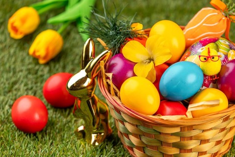 A basket with colorful eggs, flowers and Easter decoration in a meadow
