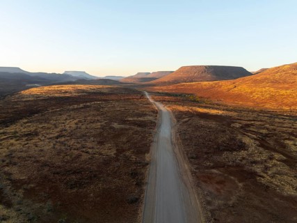 Aerial view, infinite space, straight road leads through dry desert landscape, hills in Damaraland,