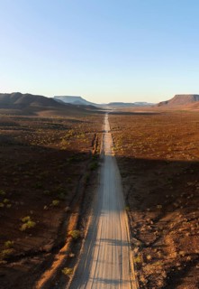 Aerial view, infinite space, straight road leads through dry desert landscape, hills in Damaraland,