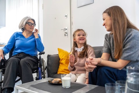 Loving three generation familygrandmother in wheelchair, mother and young daughter sharing smiles,