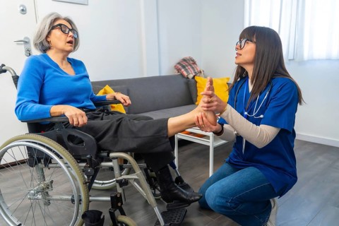 Medical professional performing a foot massage and rehabilitation exercises on an elderly patient