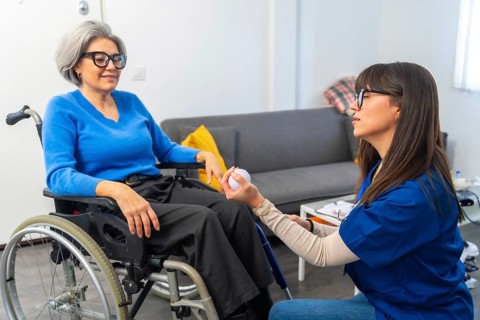 Caregiver working with a senior woman in a wheelchair, providing assistance and support during