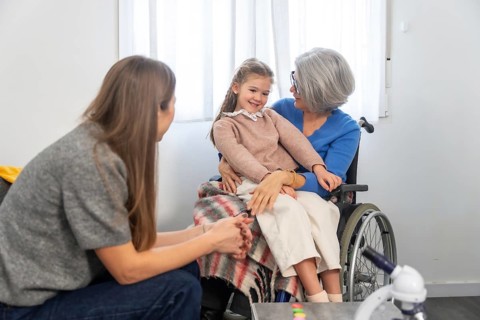 Family members connecting during a visit, with a smiling granddaughter sitting comfortably on her