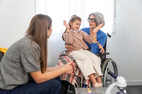 Family members connecting during a visit, with a senior woman in a wheelchair holding her