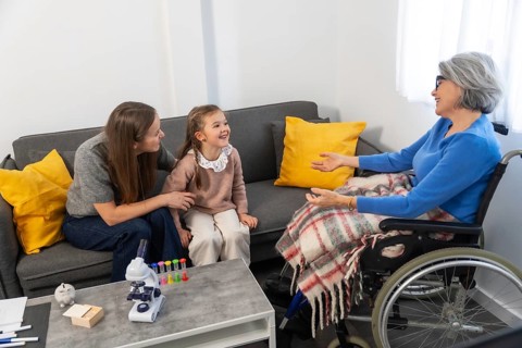 Three generations of family members warmly interacting, an elderly woman in a wheelchair engaging