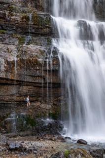 Little hiker in front of large Cascata di Mezzo waterfall, long exposure, Vallesinella, Brenta,
