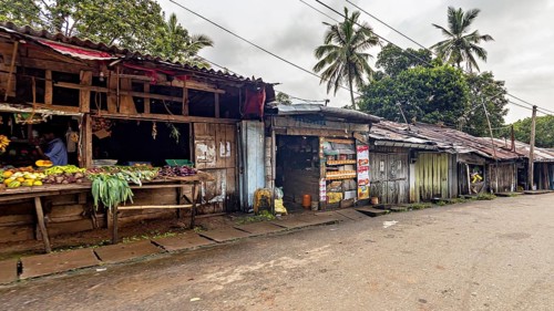 Abandoned street market area with wooden huts and tropical palm trees, small shops on the side of a