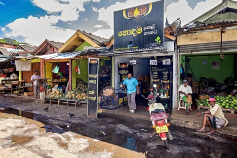 Rural street scene with small shops and people standing on the side of the road, The old market