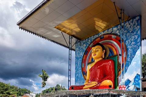 Large Buddha statue under a roof surrounded by rainbow and cloudy sky, Buddha statue in Kandy in