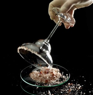 The glass rim of a margarita bowl is prepared with a salt and spice mix for the cocktail, studio