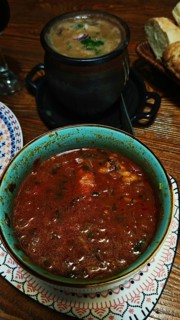 Green bowl with a delicious, rich red Georgian soup, Kharcho and a black pot in the background on a