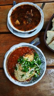 Two bowls of soup, Kharcho, served on a wooden table, one with chunky stew and the other with a red
