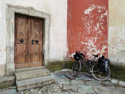 A bicycle parked in front of an old wooden door in a weathered church wall, Czech Republic