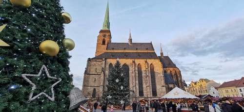 Christmas market in front of a big church with festive decoration and people, Pilsen, Czech