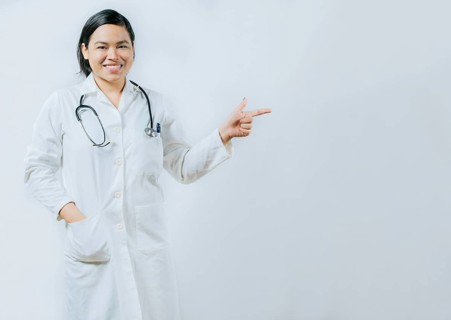 Asian female doctor pointing at medical banner isolated. Young asian female doctor recommending an