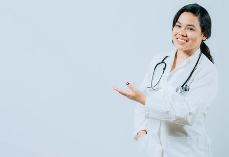 Smiling asian female doctor showing empty space isolated. Young asian doctor presenting something